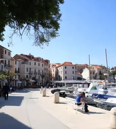 Sunny stone promenade in Vis Town with docked boats and Mediterranean houses