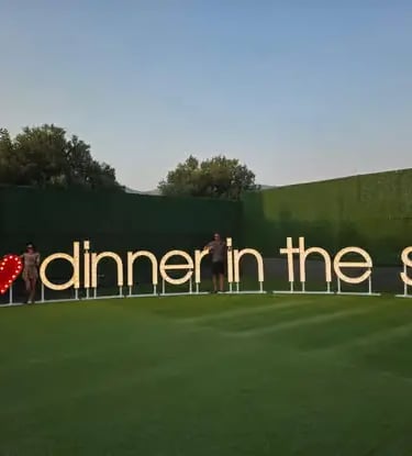 Guests posing at illuminated I Love Dinner in the Sky sign on Dubrovnik launch site lawn