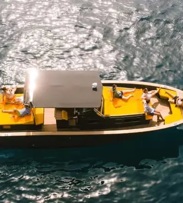 Aerial drone view of guests relaxing on a private boat in crystal-clear water