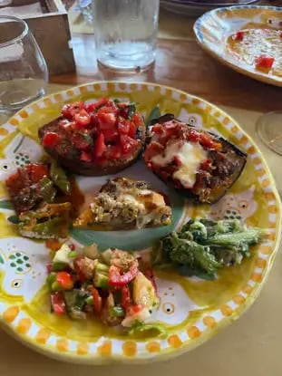 Colorful appetizer plate with bruschetta and fresh vegetables on hand-painted Italian ceramic