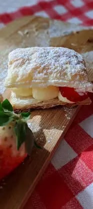 Sporcamuss pastry with cream filling and fresh strawberry on wooden board with checkered cloth