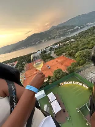 Guest holding white wine with aerial Adriatic coastline sunset view at Dinner in the Sky Dubrovnik