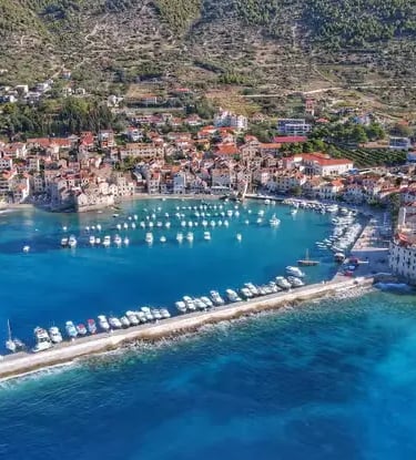Aerial drone view of Komiža fishing village and turquoise harbor on Vis Island Croatia