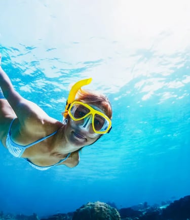 Woman snorkeling underwater in crystal clear blue water near Positano Amalfi Coast