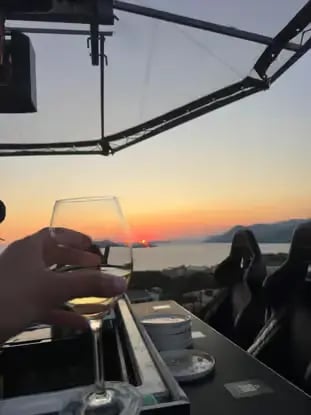 Guest holding wine glass at sunset on Dinner in the Sky platform above Dubrovnik coast
