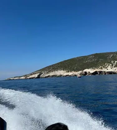 View from speedboat racing across Adriatic Sea toward Croatian island cliffs on sunny day