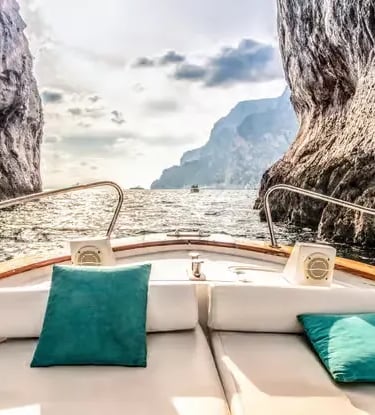 Private tour boat passing between limestone cliffs on Amalfi Coast snorkeling stop