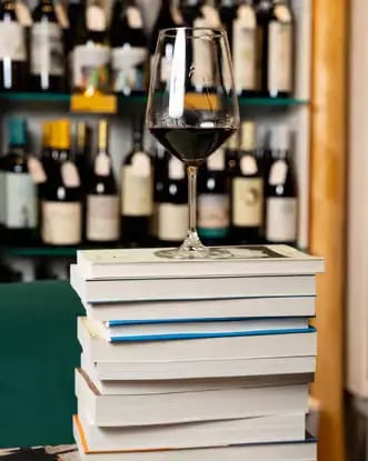Glass of Primitivo wine on a stack of books with wine bottles in the background