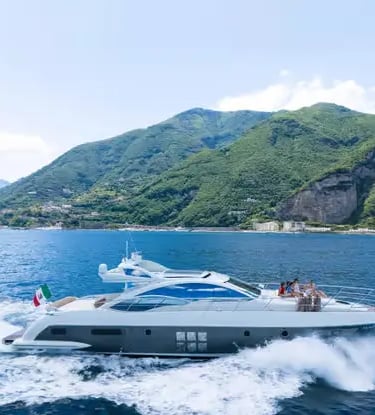 Azimut luxury yacht cruising at speed along green Italian coastline with Italian flag