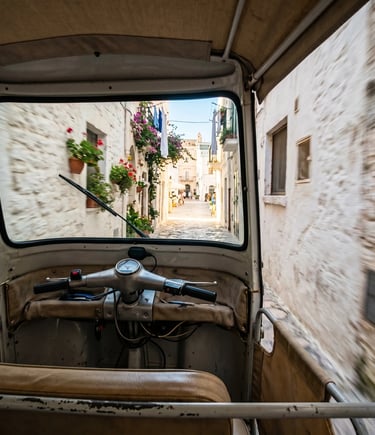 POV from inside Ape Calessino driving through narrow white-walled Puglia alley