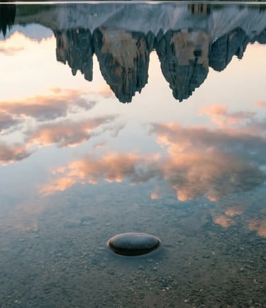 Tre Cime di Lavaredo reflected in still Alpine lake water with smooth stone