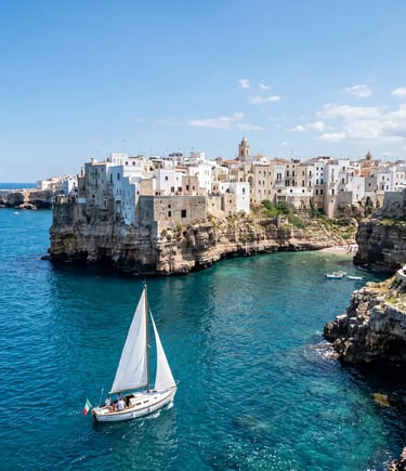 White sailboat sailing in front of Polignano a Mare cliffs and white houses on Adriatic coast