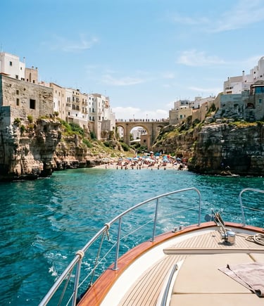Yacht bow approaching Lama Monachile beach and Roman bridge in Polignano a Mare from the sea