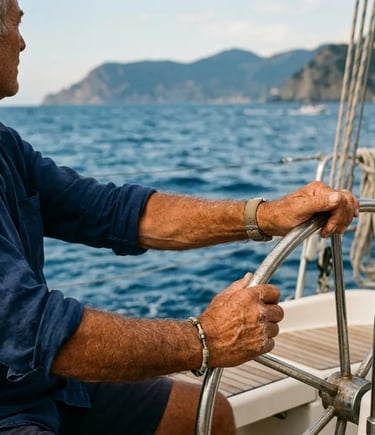 Experienced Italian skipper gripping a stainless steel boat wheel on the Ligurian Sea