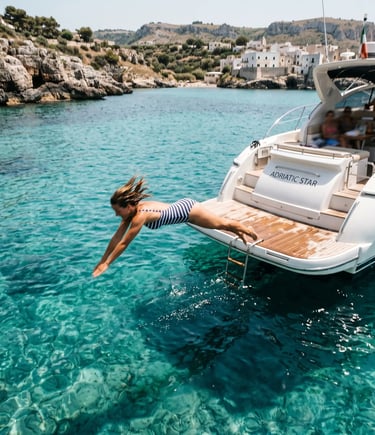 Woman diving off Adriatic Star charter boat into turquoise water near Castro Puglia limestone cove