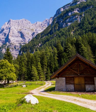 Rustic wooden barn on green alpine meadow below dramatic Dolomite cliffs