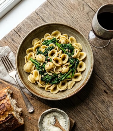 Handmade orecchiette pasta with cime di rapa, bread and red wine on rustic wooden table