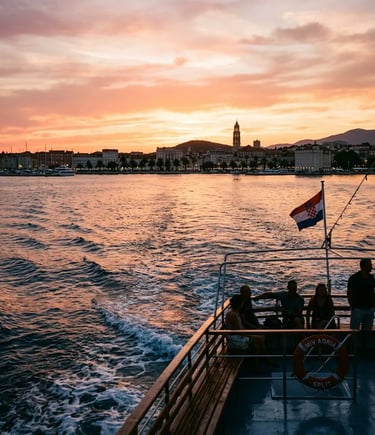 Boat returning to Split at sunset with Croatian flag and city skyline in golden light