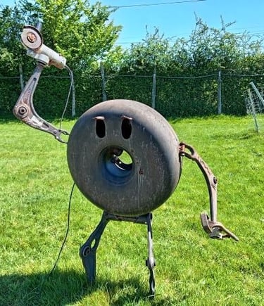 A creative metal sculpture of a character made from recycled scrap metal and car parts in a green field.