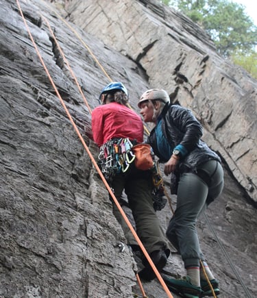 Two people in conversation while climbing a rock face outdoors