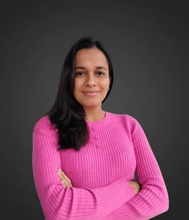 Professional woman in a pink ribbed sweater posing with arms crossed against a dark background.