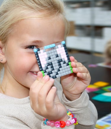 Happy girl showing the picture of an elephant made of colorful silicone pixel squares