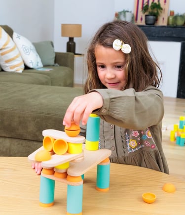 The girl is creating a unique construction from colorful silicone and wooden figures