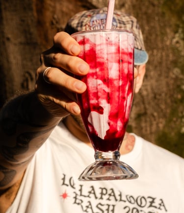 a man holding a milkshake in front of a tree