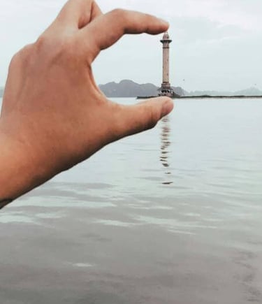 a person holding a small light house in the water