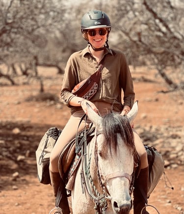 jeune femme souriante à cheval dans la campagne marocaine