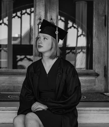 a woman in a graduation gown sitting on the steps