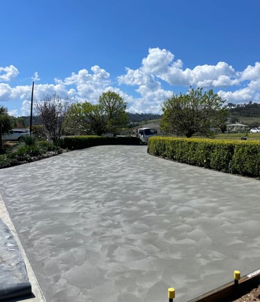 Freshly poured decorative concrete driveway with hand-troweled swirl finish in a residential landscape.