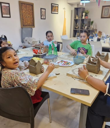 Children and a teacher engaged in a creative teracotta clay sculptures at a pottery studio table.