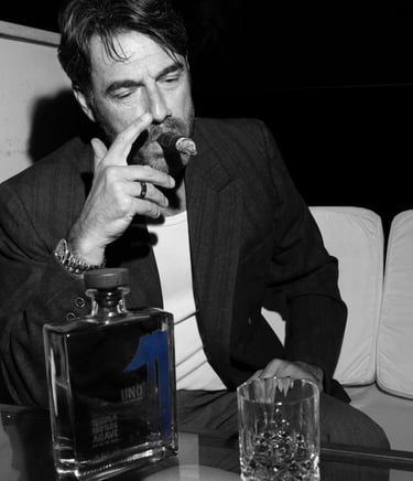a man in a suit and tie is drinking a glass of uno tequila