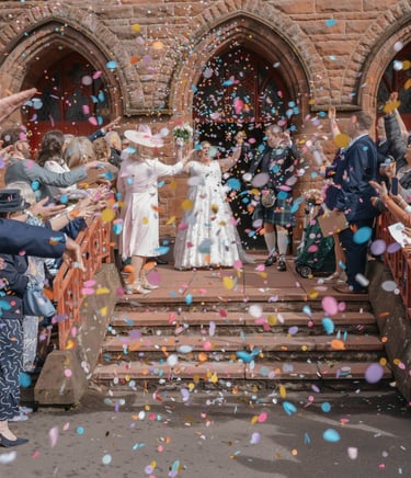 Wedding guests throw colorful confetti at a bride and groom exiting St Augustine’s church Coatbridge