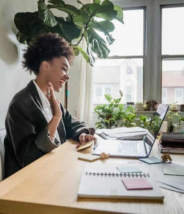 a woman sitting at a desk with a laptop and a notebook