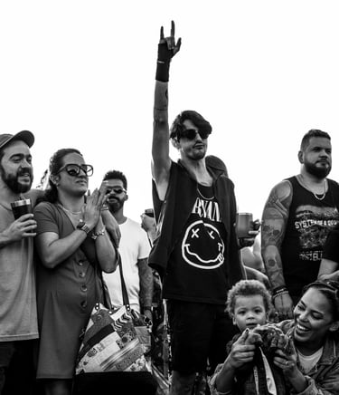 homem no publico fazendo dedos de rock em contraste com um publico familia e sorridente