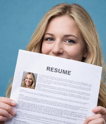 A blonde woman smiling while holding her professional resume for a job application or career interview.