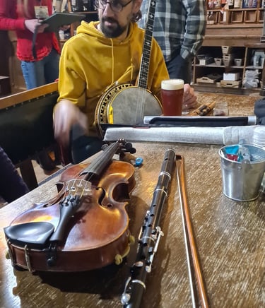 Traditional Irish music session featuring a fiddle, flute, and banjo on a pub table.