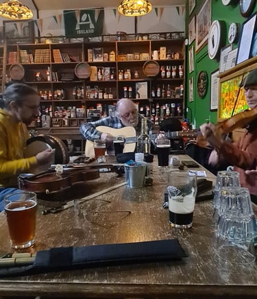 Musicians playing traditional Irish folk music with guitars and fiddles inside a rustic pub.