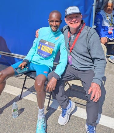 John Korir, wearing his Kenya singlet and gold medal, stands with his coach Ron Mann After boston marathon