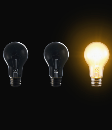 a group of three light bulbs with a glowing yellow light bulb