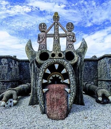 Mystical stone monster sculpture by Rober Tatin with a large open mouth and carved tribal figures