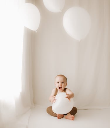 baby holding balloons for a cake smash photo session in Littlehampton studio