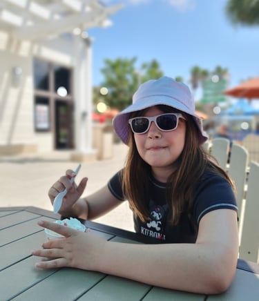 a woman in a hat and sunglasses sitting at a table