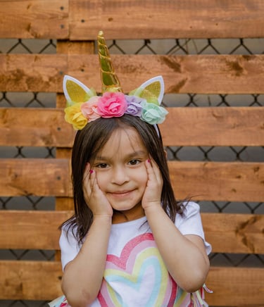 Little girl with hands on face wearing a unicorn headband