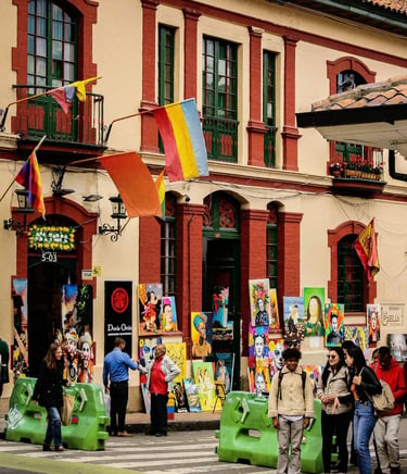 Local paintings displayed for sale outside a colonial house with visitors walking in La Candelaria town