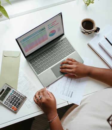 Lady sitting at a desk with a laptop and calculator working on tracking her bills.