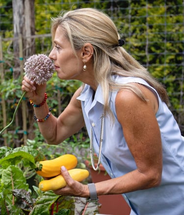 a woman in a blue shirt is holding a Garlic Chive Blossom