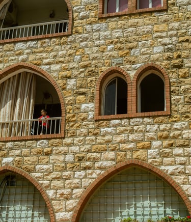 Photography Child standing on a balcony of building with arched windows in Brummana, Lebanon